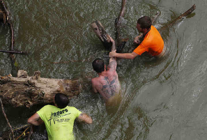 After he fell off an inner tube into the Licking River near Straddens Bridge Road family and friends of James Krofft (from left) Dallas Powelson, Andrew Anderson, and Adam Smith search for the 22-year-old Newark man under the Pleasant Valley Road bridge several miles down river in Nashport, Ohio on June 25. Krofft's body was found by ODNR searchers the following day.  (Adam Cairns / The Columbus Dispatch)